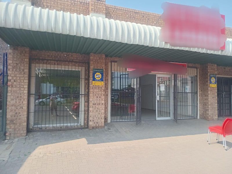 Commercial storefront featuring a face brick facade, corrugated metal awning, and secure metal gates over glass display windows.