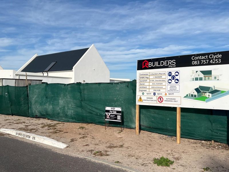 A construction site view showing a property under development with site signage and perimeter fencing.