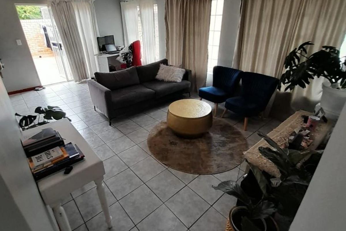 A living room area featuring neutral tiled flooring and direct access to an outdoor patio through a sliding glass door.