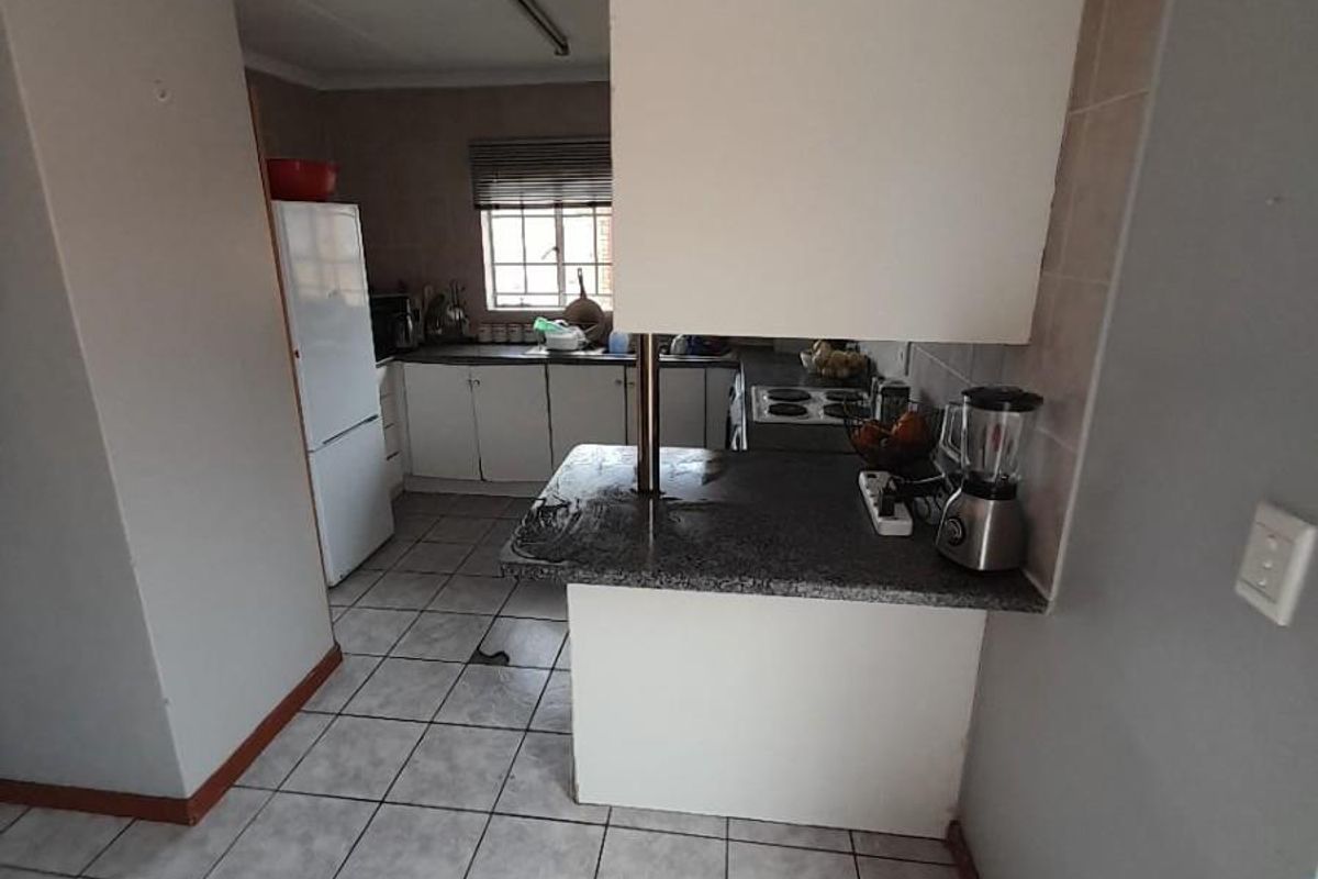 Functional kitchen featuring built-in cabinetry, laminate countertops, a breakfast bar, and tiled flooring, offering a practical layout with potential for modern updates.