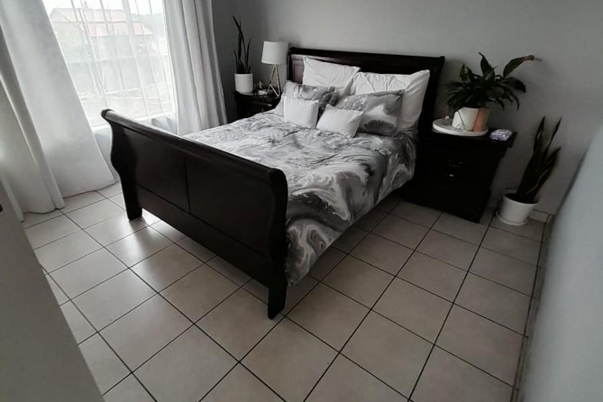 A bedroom featuring tiled flooring, a window with grid detailing, and coved ceiling finishes.