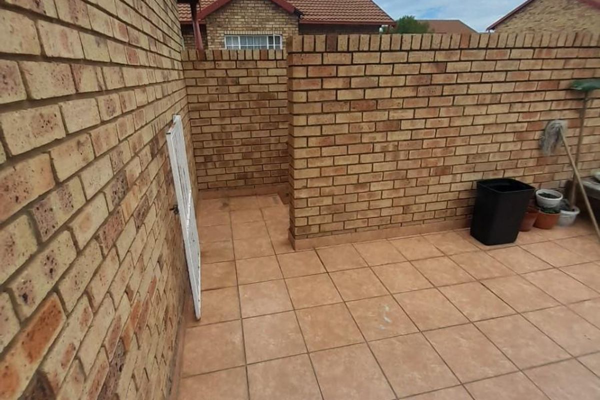 A private rear courtyard area featuring face brick walls and tiled flooring, providing a functional outdoor space for the townhouse.