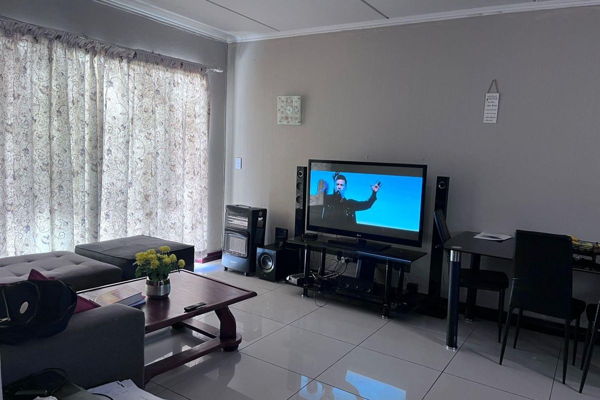 A living room featuring large format floor tiles and a sliding door with curtain tracks.