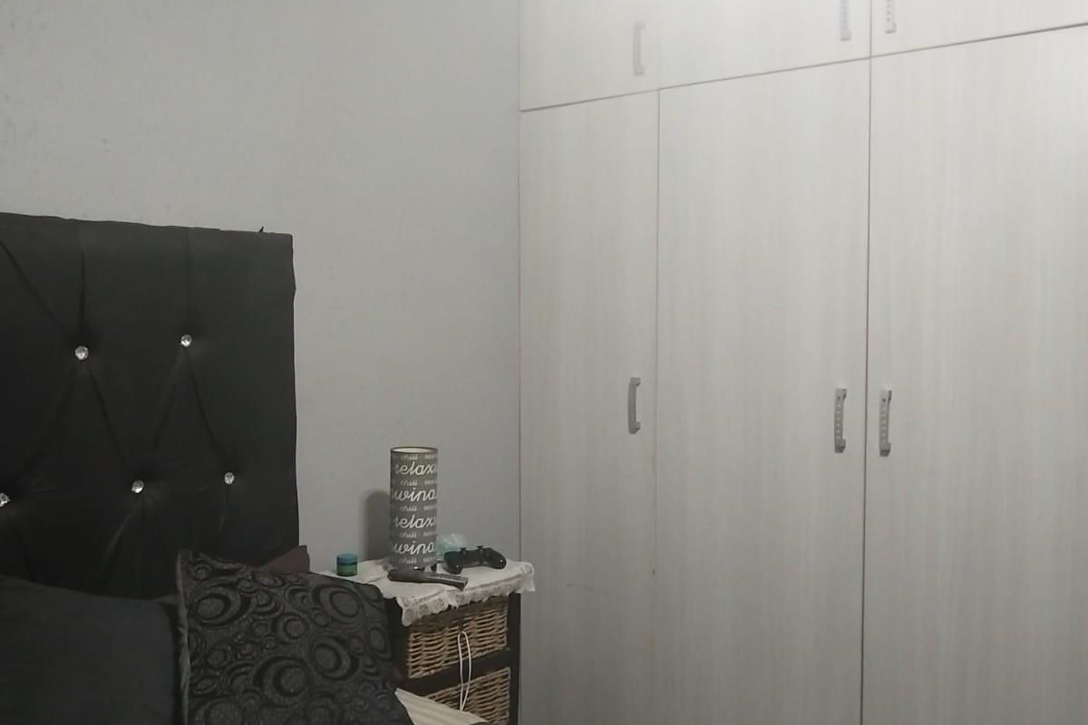 A bedroom featuring built-in floor-to-ceiling wardrobes with light wood-grain finish and neutral wall paint.