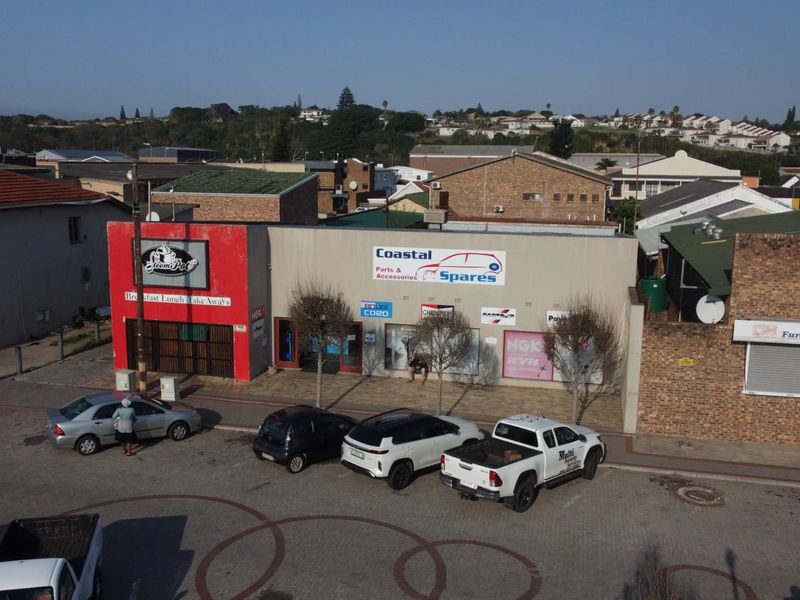 Aerial view of a commercial strip center featuring multiple storefronts with signage and paved parking area.