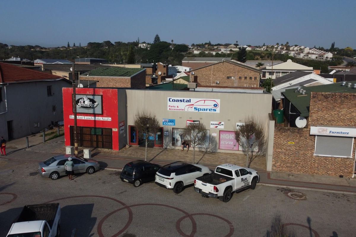 Aerial view of a commercial strip center featuring multiple storefronts with signage and paved parking area.