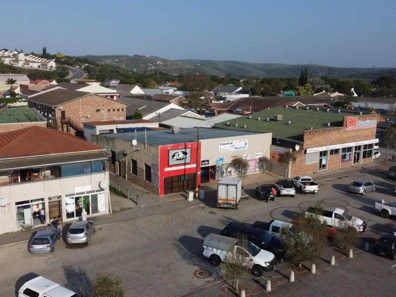 Aerial view of a commercial retail strip center featuring multiple storefronts, paved parking area, and surrounding suburban landscape.