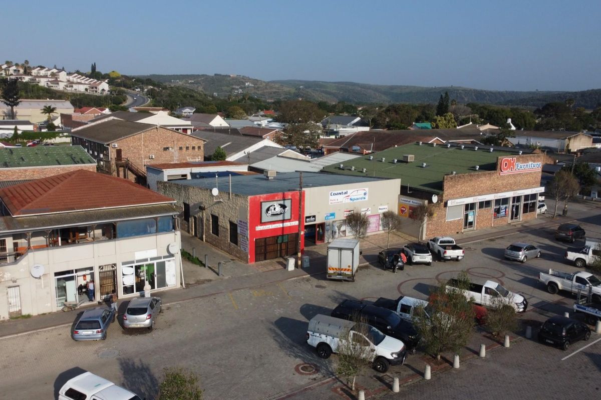 Aerial view of a commercial retail strip center featuring multiple storefronts, paved parking area, and surrounding suburban landscape.