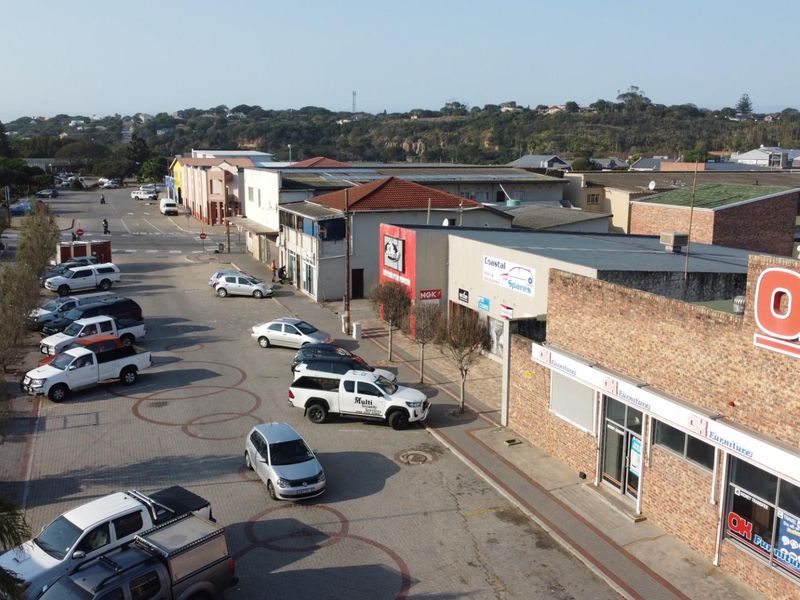 Aerial view of a commercial street featuring retail storefronts, paved parking areas, and surrounding neighborhood infrastructure.