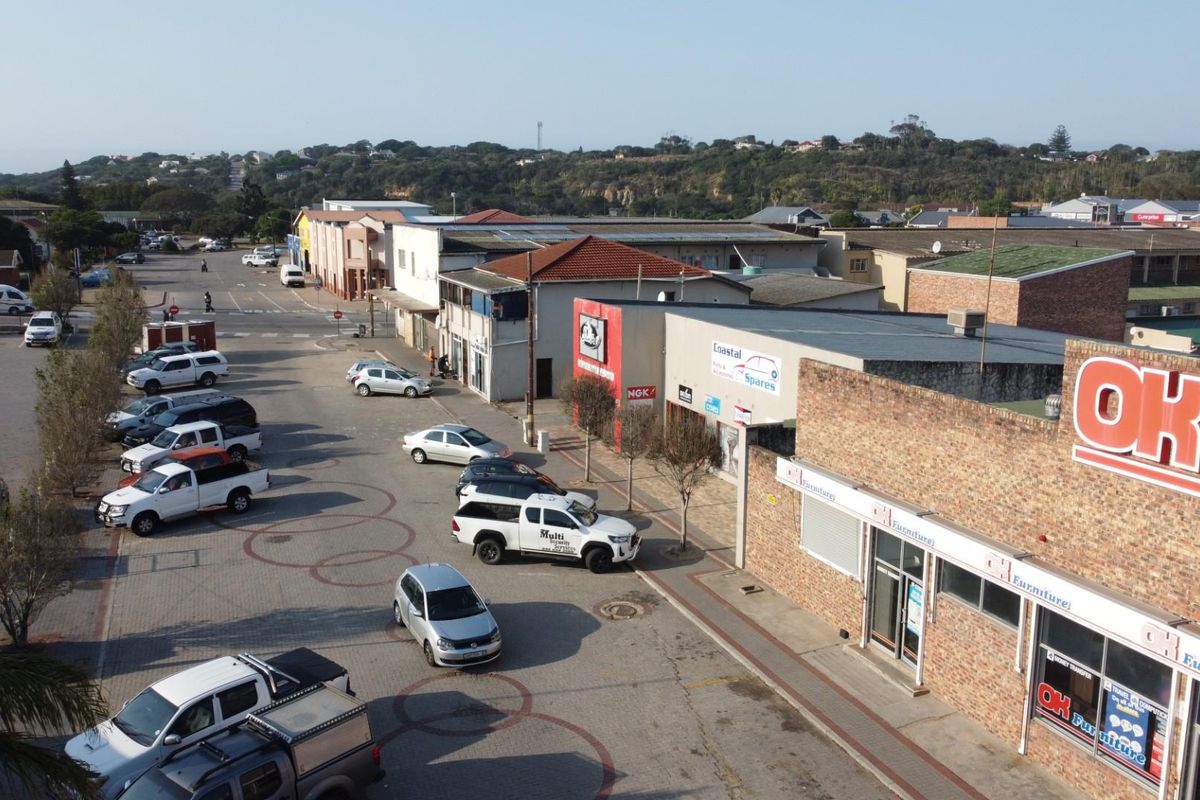 Aerial view of a commercial street featuring retail storefronts, paved parking areas, and surrounding neighborhood infrastructure.