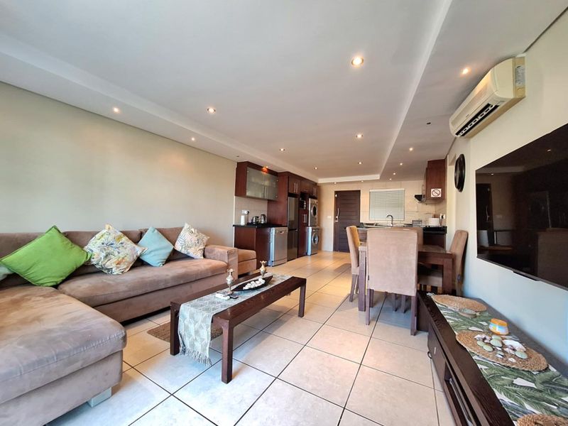 Spacious open-plan living and dining area featuring tiled flooring, recessed lighting, a split-system air conditioner, and a functional kitchen with built-in cabinetry.