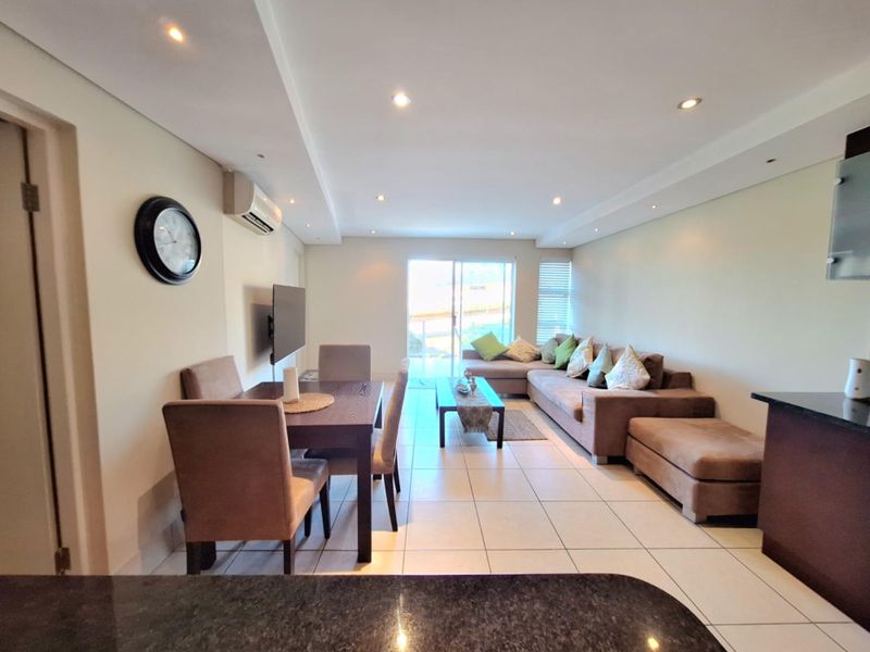 Spacious open-plan living and dining area featuring tiled floors, recessed lighting, air conditioning, and direct access to an outdoor space via sliding doors.