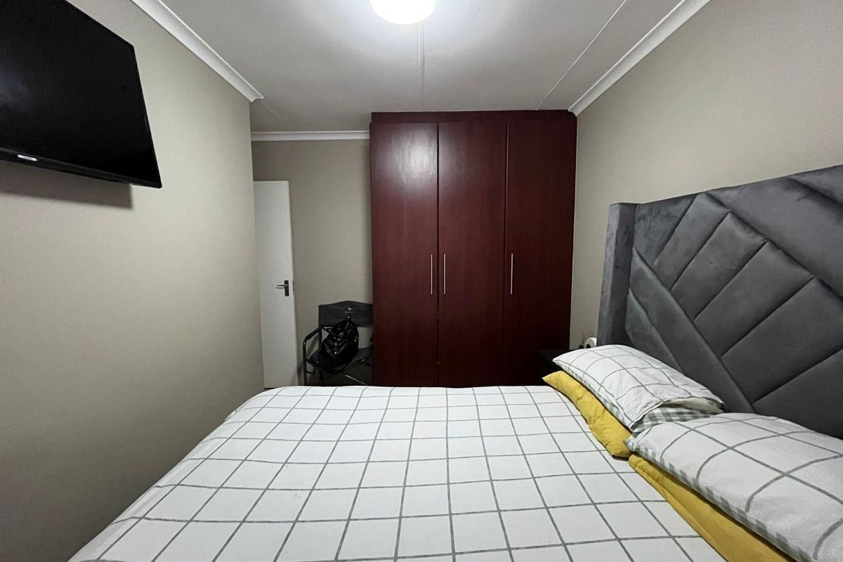 A well-maintained bedroom featuring a dark wood built-in wardrobe, neutral wall tones, and cove cornice detailing.