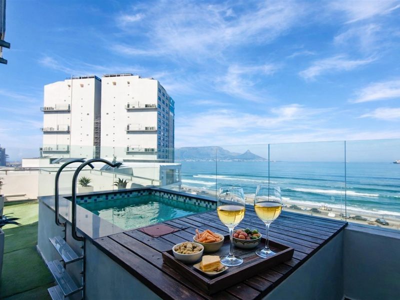 A private balcony featuring a plunge pool with glass balustrades, offering panoramic ocean and mountain views.