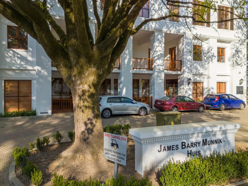 Front exterior view of the James Barry Munnik office building, featuring a paved parking area, mature tree, and classic architectural facade.