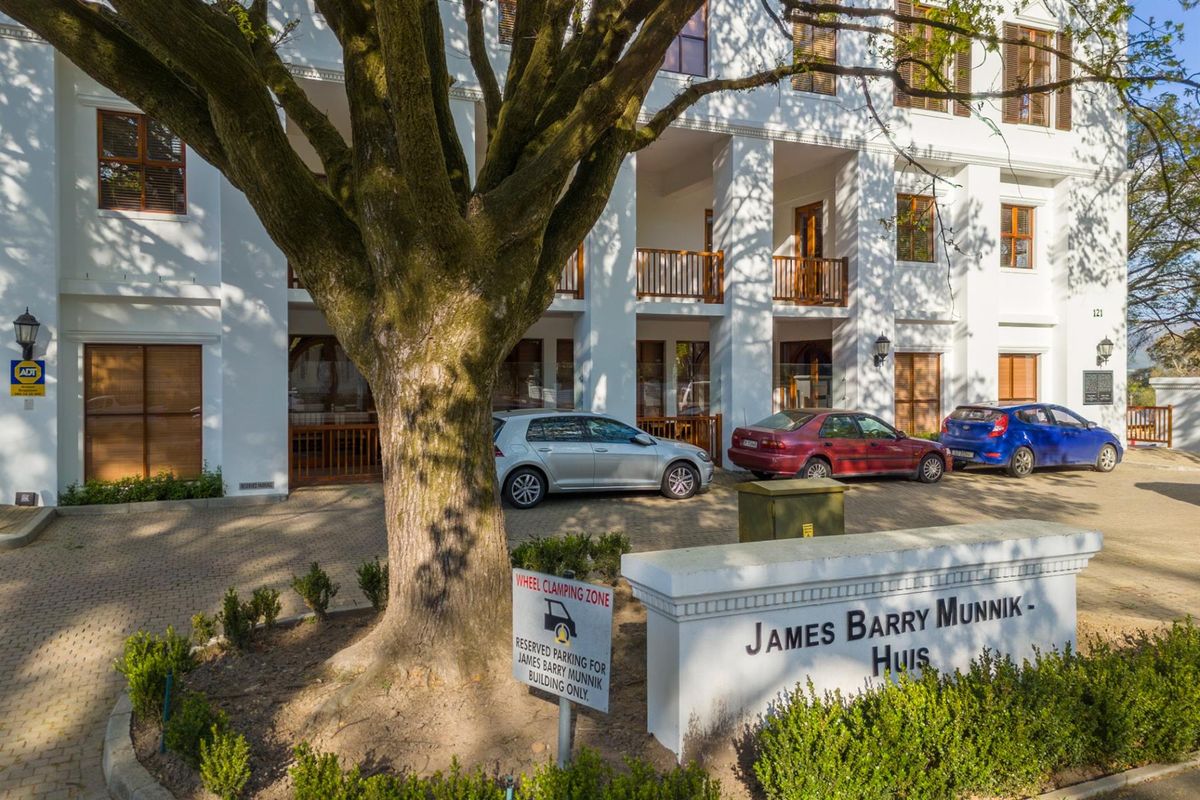 Front exterior view of the James Barry Munnik office building, featuring a paved parking area, mature tree, and classic architectural facade.