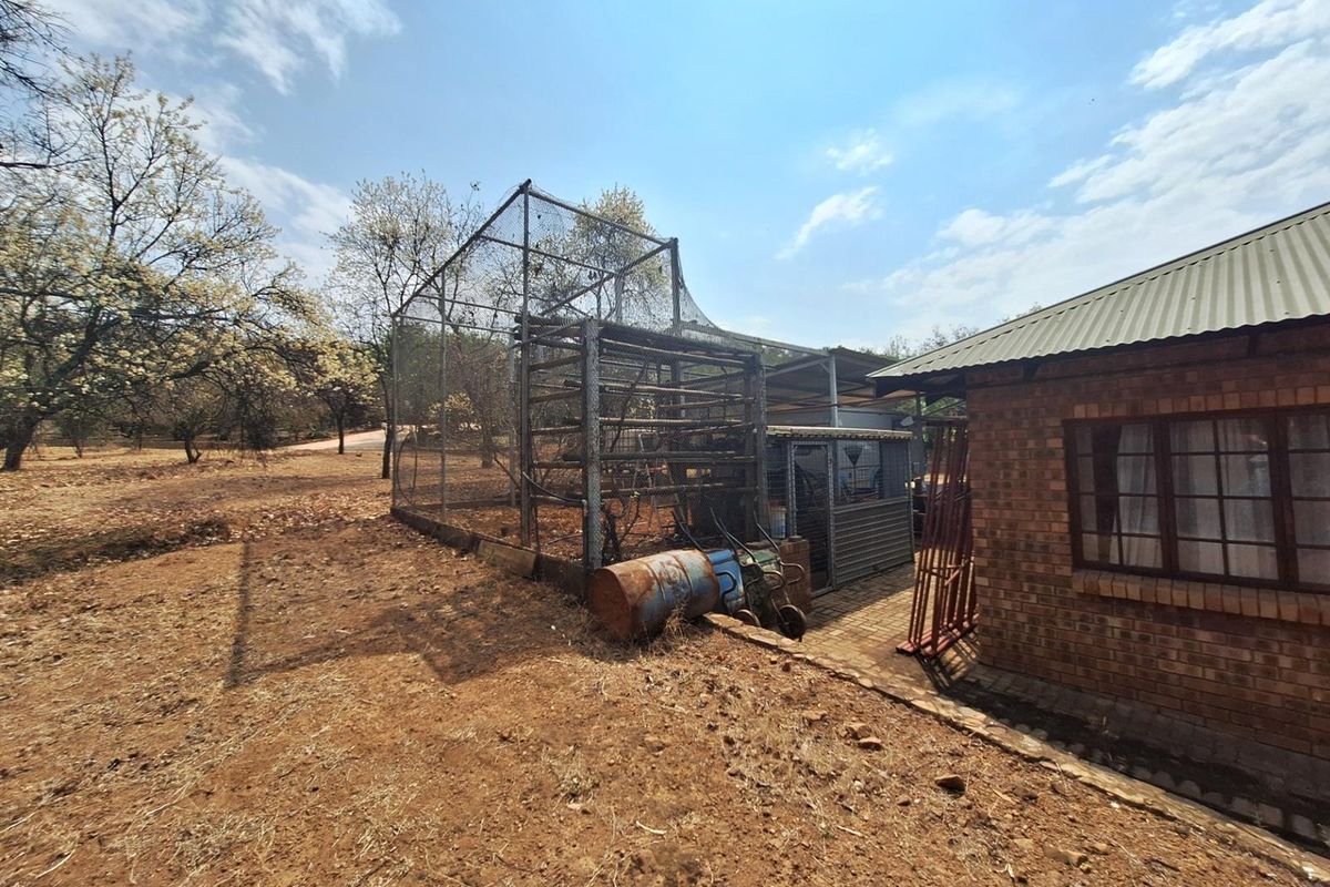 Exterior view of the property featuring a large metal mesh enclosure and brick wall construction, set within a dry, unlandscaped outdoor area.