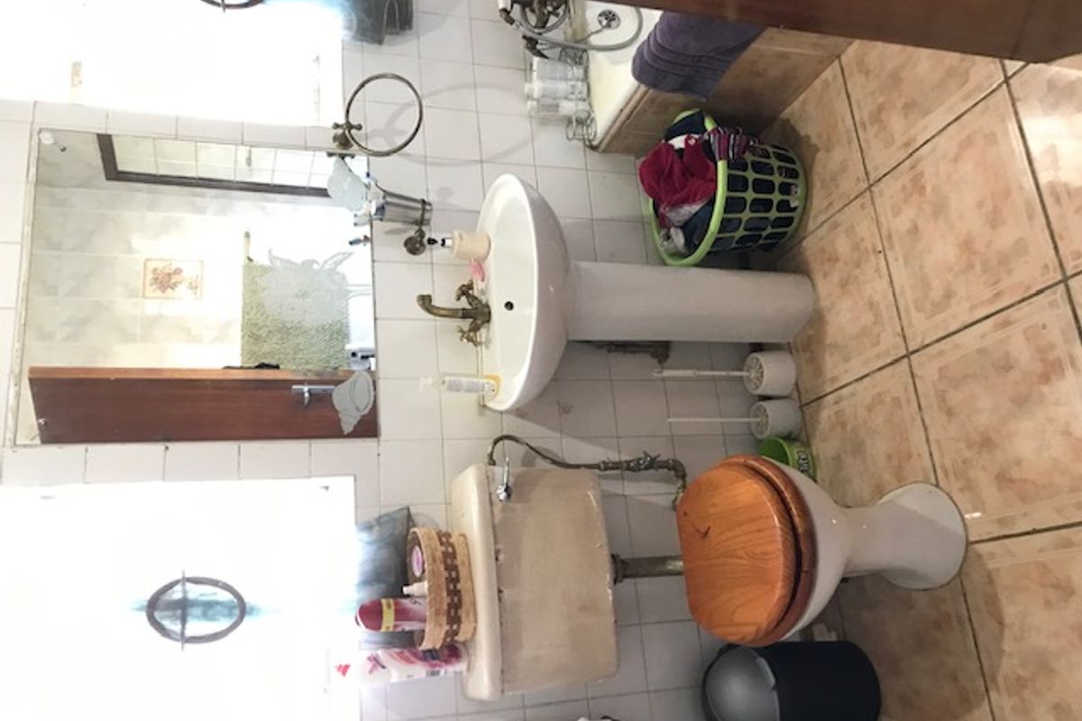A dated bathroom featuring a pedestal sink, standard toilet, and tiled finishes, requiring modernization to improve functionality and aesthetic appeal.
