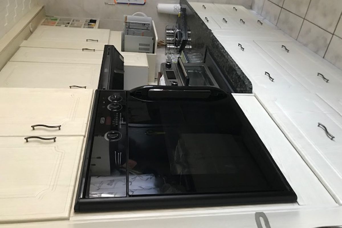 A functional kitchen featuring light-toned cabinetry, dark granite countertops, tiled flooring, and a built-in black oven.