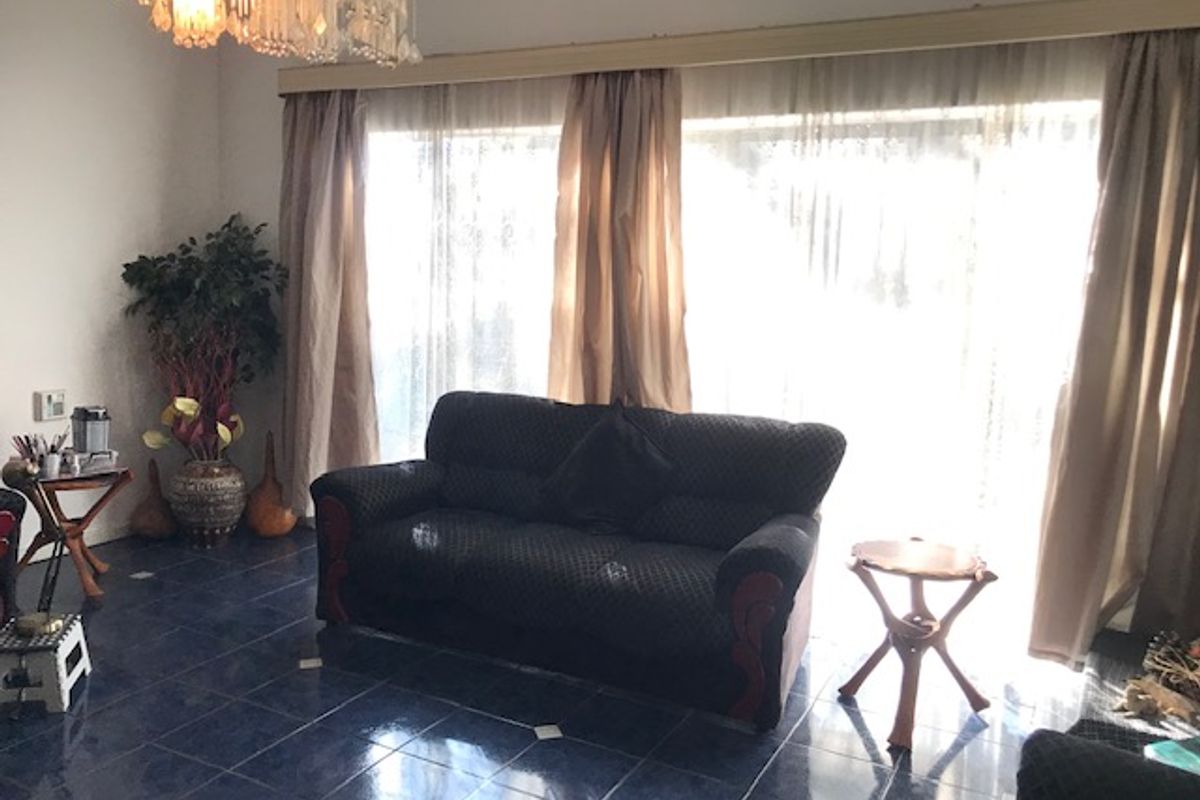 A living room featuring large glass sliding doors with curtains and dark blue tiled flooring.