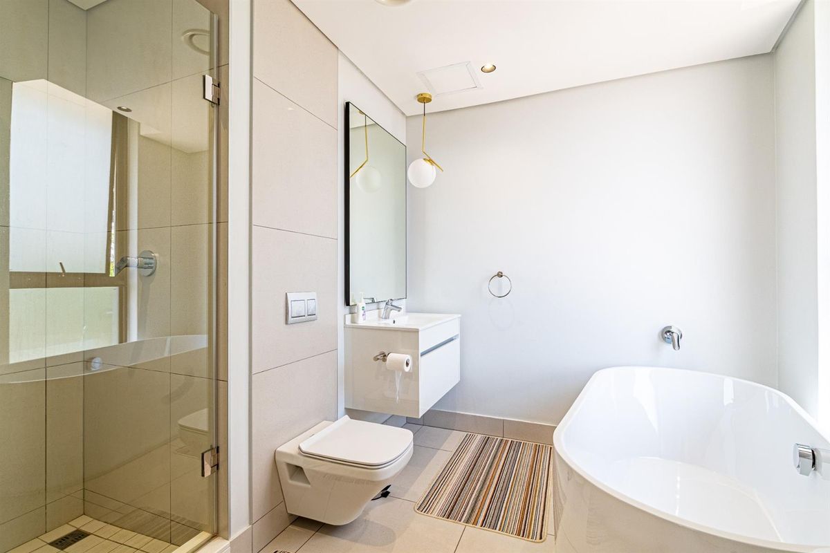 Modern bathroom featuring a wall-mounted vanity, a sleek freestanding bathtub, a wall-hung toilet, and a glass-enclosed shower with contemporary finishes.