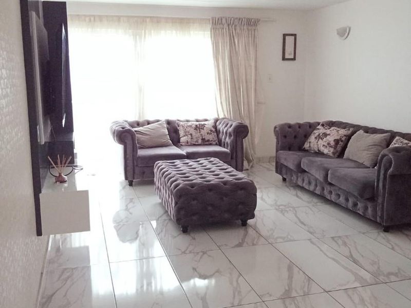Spacious living room featuring large format marble-look porcelain floor tiles and a modern wall-mounted media console unit.