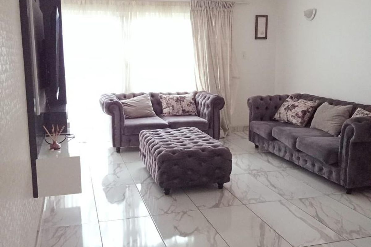 Spacious living room featuring large format marble-look porcelain floor tiles and a modern wall-mounted media console unit.