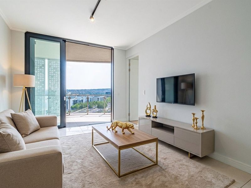 A bright and modern living room featuring tiled floors, recessed lighting, and large sliding glass doors that open onto a balcony with city views.