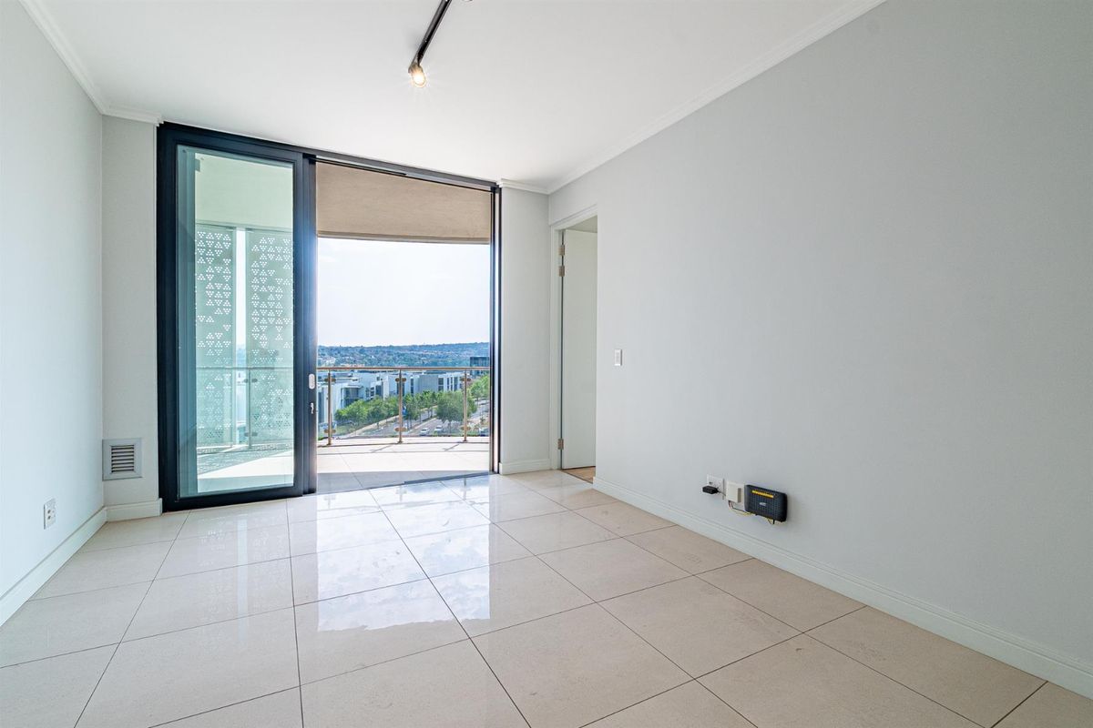 Bright and spacious living area featuring large sliding glass doors leading to a private balcony with scenic views and modern tiled flooring.