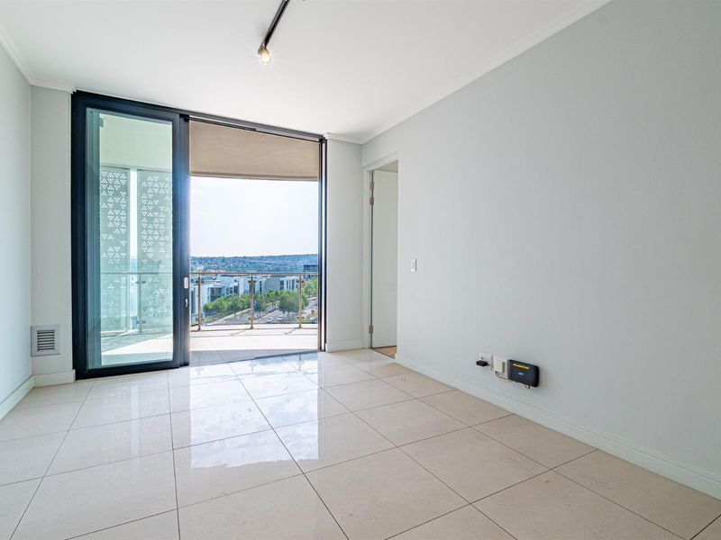 Bright and spacious living area featuring large sliding glass doors leading to a private balcony with scenic views and modern tiled flooring.