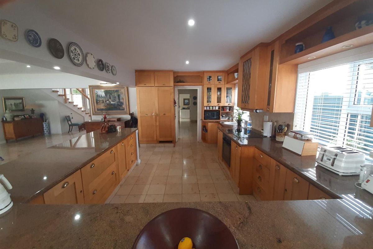 Spacious kitchen featuring extensive wooden cabinetry, granite countertops, integrated appliances, and tiled flooring, offering a functional layout with ample storage space.