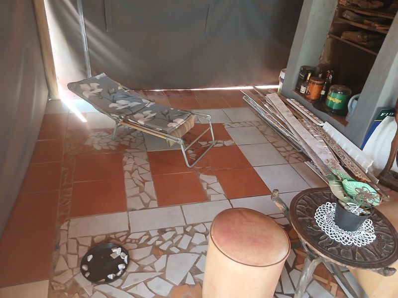 A covered patio area featuring a built-in fireplace, tiled flooring with decorative inlay, and protective canvas blinds.