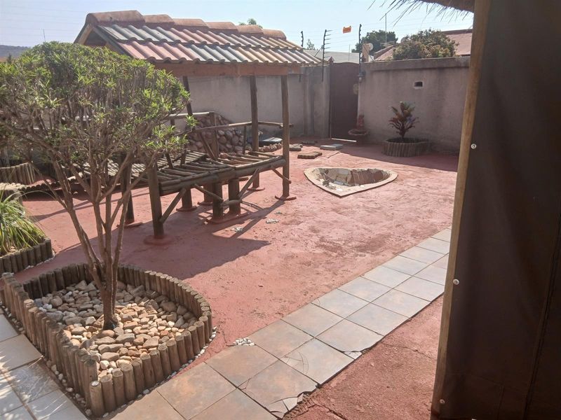 Rear courtyard area featuring a timber gazebo, raised garden beds, and a paved patio with perimeter walling and electric fencing.