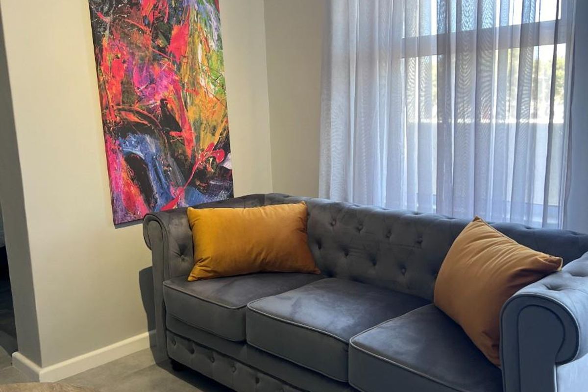 A well-maintained living area featuring large format floor tiles and a window with fitted curtain tracks.
