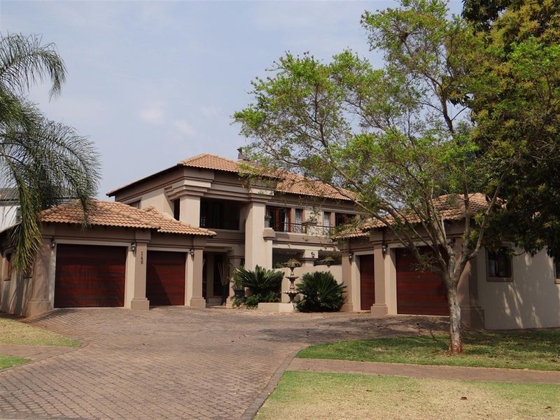 A well-maintained double-story residence featuring a triple garage, paved driveway, and classic terracotta roof tiles with a prominent front entrance.