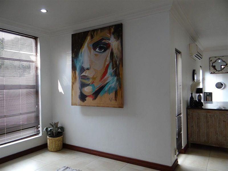 A bright living area featuring tiled flooring, recessed downlighting, and a wall-mounted split-system air conditioner.