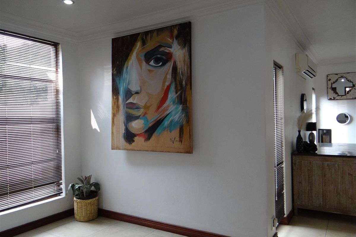 A bright living area featuring tiled flooring, recessed downlighting, and a wall-mounted split-system air conditioner.