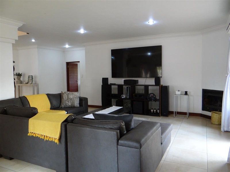 Spacious living room featuring tiled flooring, recessed downlights, and a built-in fireplace, creating a comfortable and functional family area.