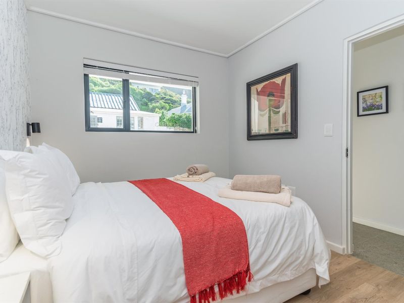 A well-maintained bedroom featuring modern laminate flooring, neutral wall finishes, and an aluminium-framed window with views of the surrounding area.