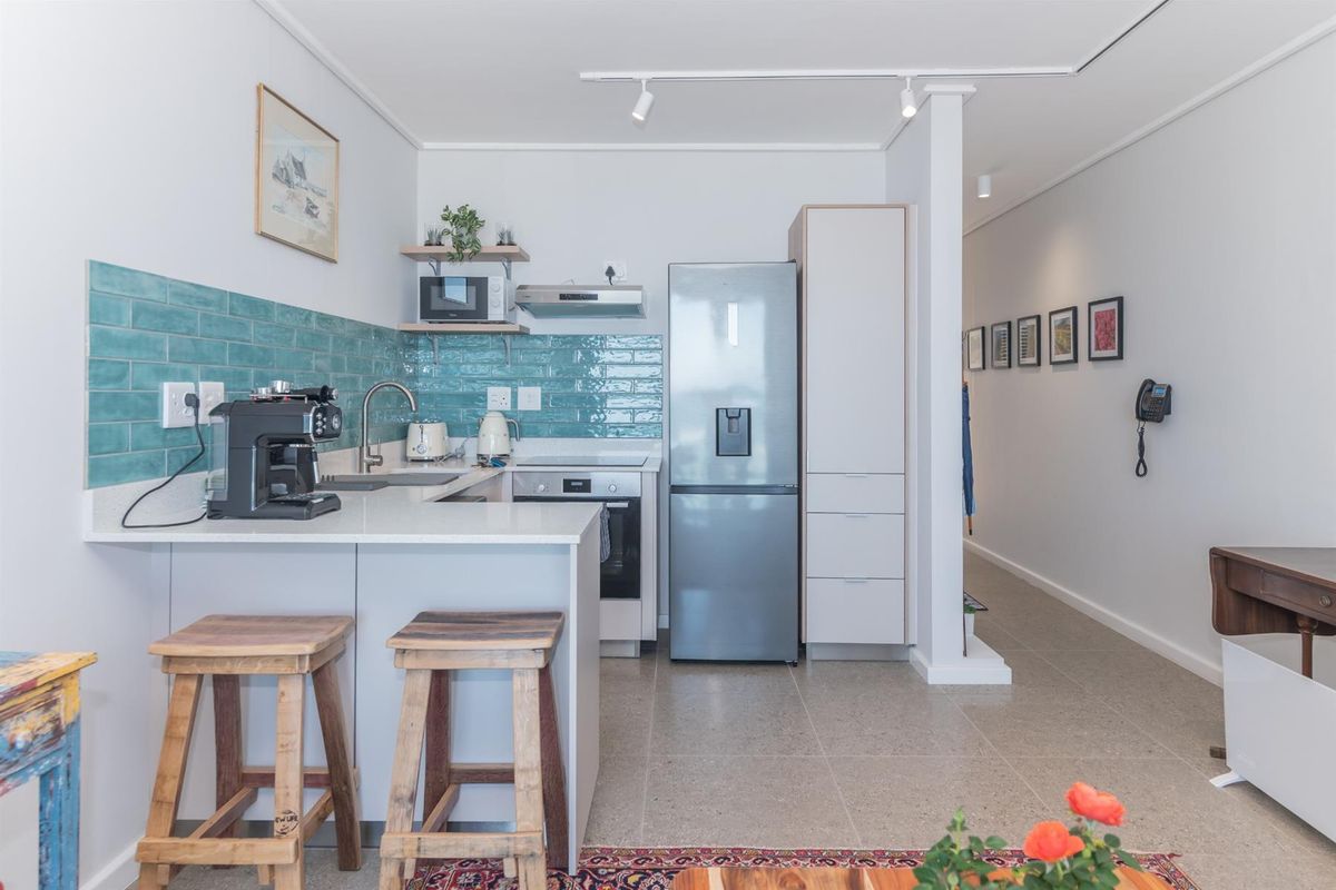 Modern kitchen featuring sleek white cabinetry, quartz countertops, a vibrant teal subway tile backsplash, and integrated stainless steel appliances.