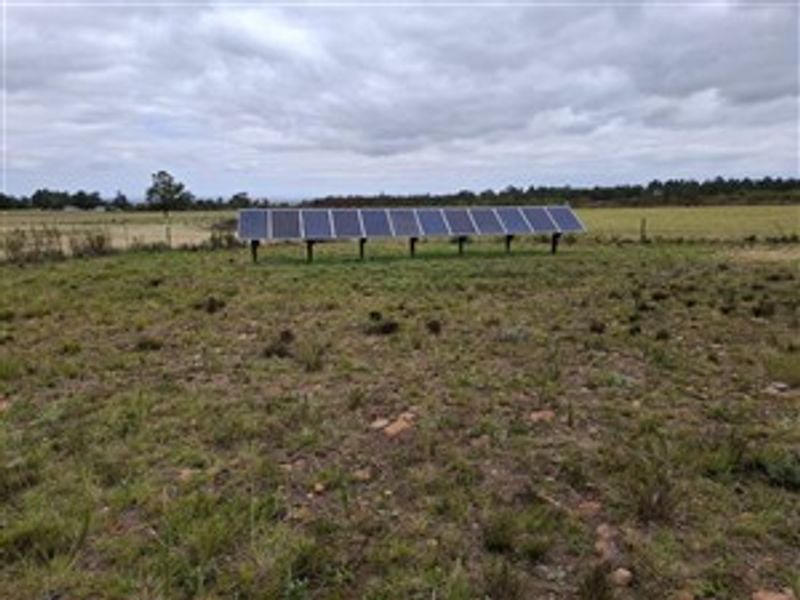 A ground-mounted solar panel array situated in an open field on the farm property.