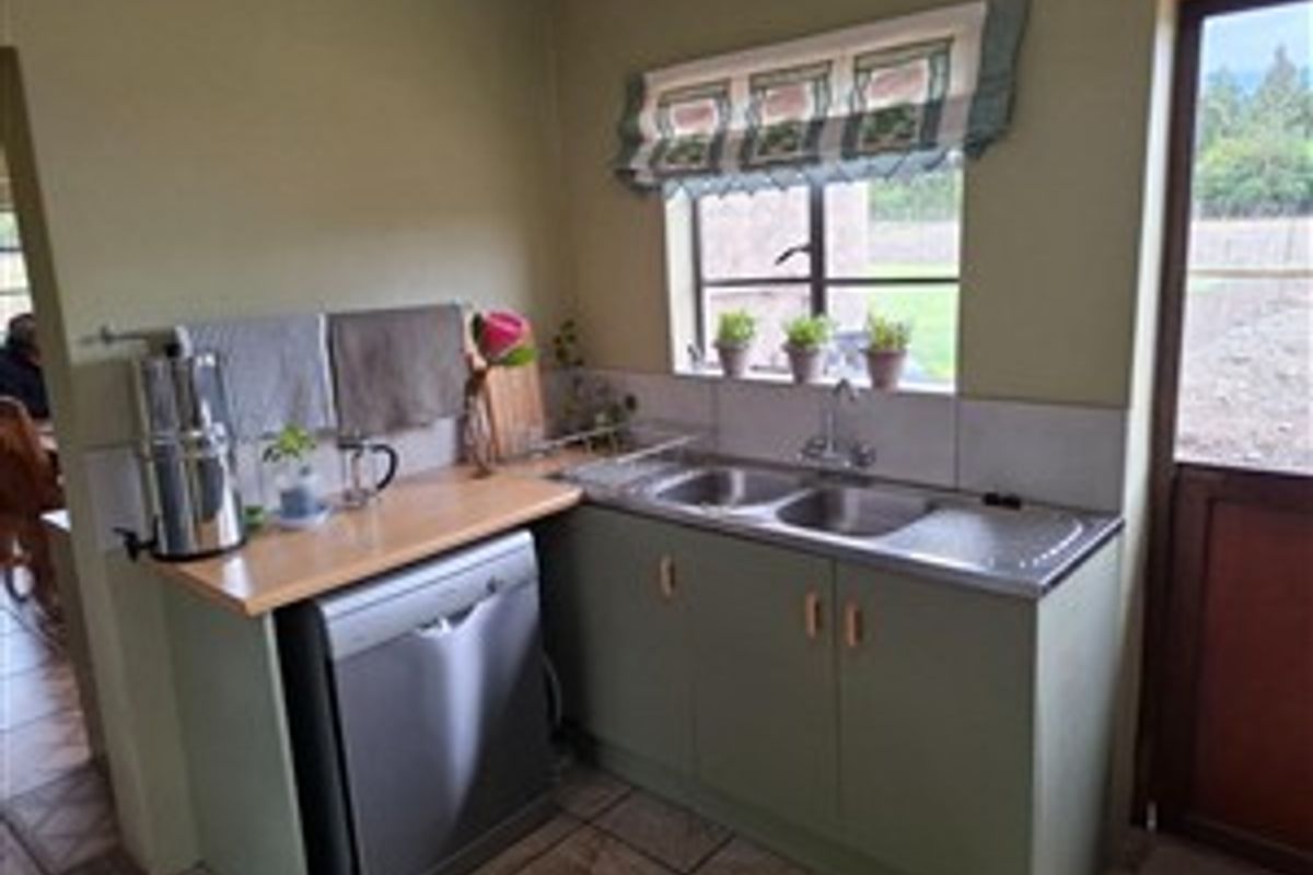 A functional kitchen area featuring a double stainless steel sink, tiled backsplash, and built-in cabinetry with a wooden countertop.