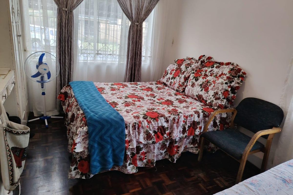 A bedroom featuring dark parquet flooring, built-in wardrobe cabinetry, and large windows with curtains.