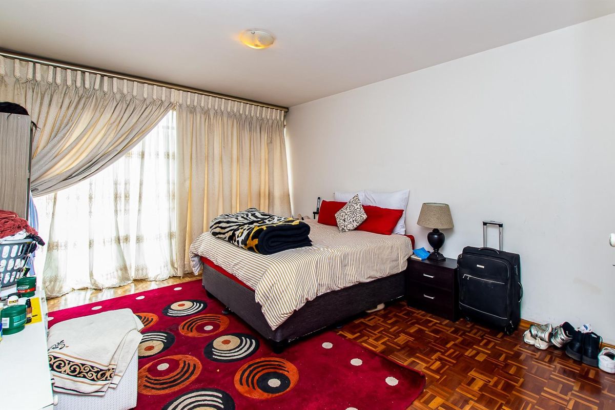A bedroom featuring classic parquet flooring and a large sliding glass door that provides access to natural light.