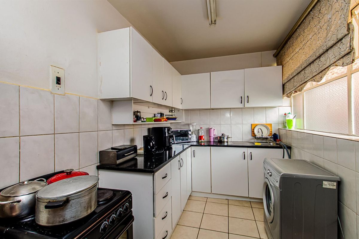 A functional kitchen featuring white cabinetry, black granite countertops, tiled backsplash, and tiled flooring, offering a practical layout for daily meal preparation.