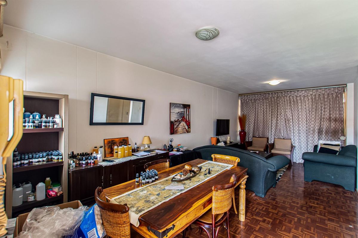 A spacious living area featuring traditional parquet flooring and neutral wall finishes, offering a versatile layout for comfortable daily living.