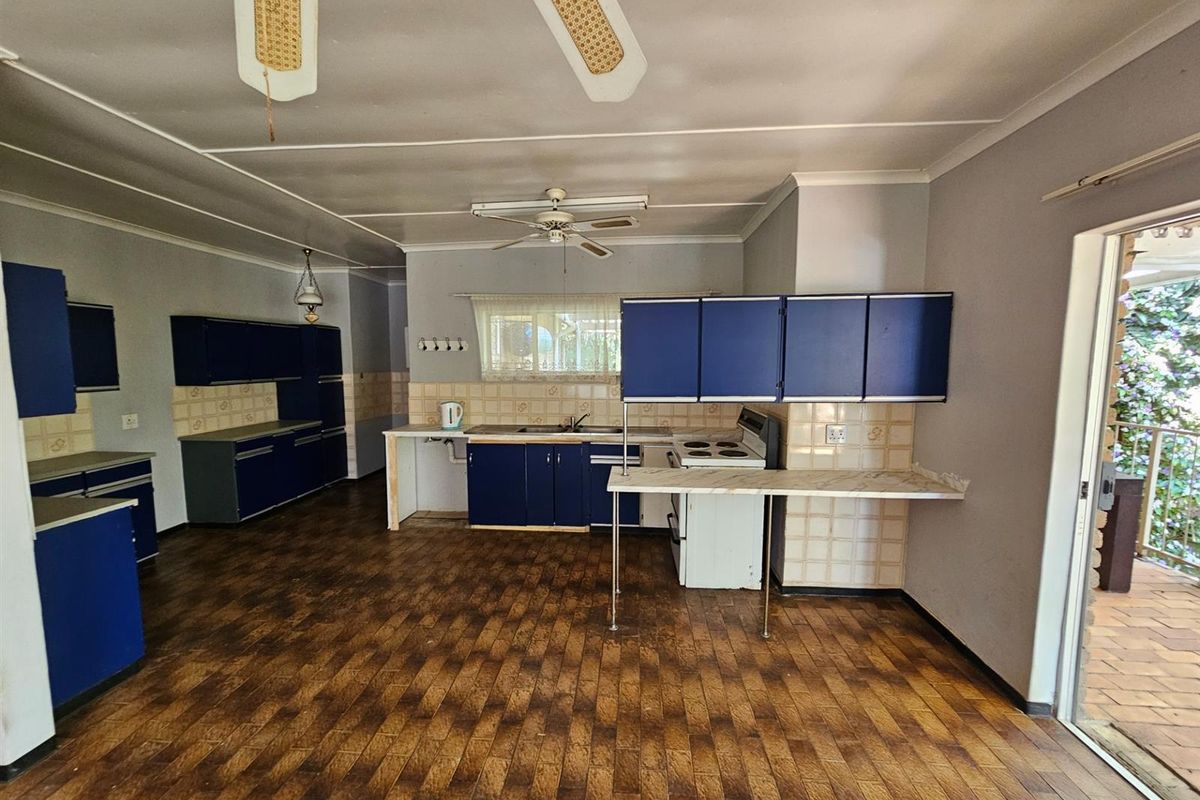 Spacious kitchen featuring blue cabinetry, tiled backsplash, and direct access to an outdoor patio area.