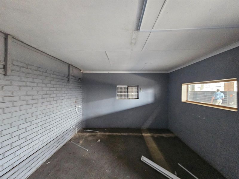 An empty industrial utility space featuring painted brick walls, a concrete floor, and horizontal windows, suitable for storage or workshop conversion.