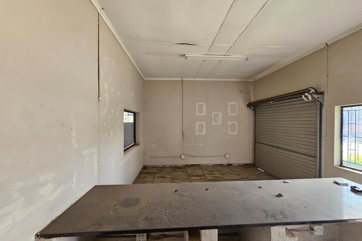 Industrial utility space featuring a roller shutter door, tiled flooring, and a built-in service counter, suitable for workshop or storage use.
