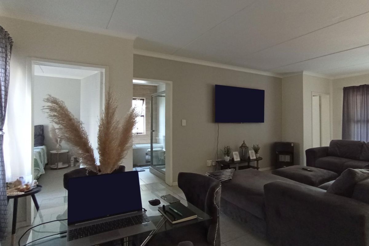 Spacious open-plan living area featuring neutral wall tones, tiled flooring, and coved ceiling details, providing a comfortable and well-maintained living space.